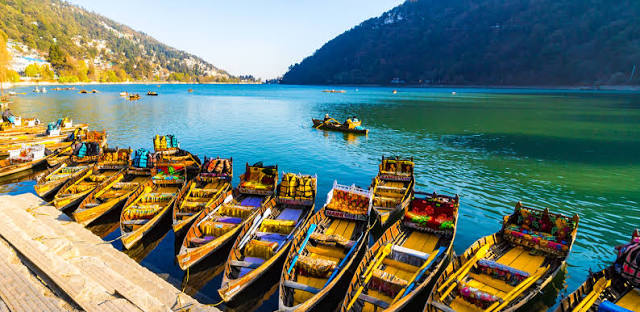 "Best Places to Visit in Uttarakhand featuring Naini Lake with colorful boats and breathtaking mountain views."