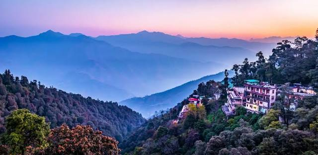 "Best Places to Visit in Uttarakhand – Panoramic view of Mussoorie with lush green hills, Himalayan mountains, and beautiful sunset scenery."