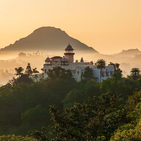 "Best Places to Visit in India – Scenic view of Neemrana Fort Palace surrounded by lush greenery and hills in Rajasthan."