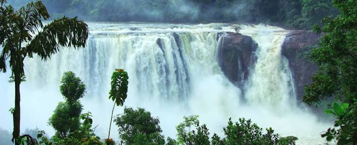 Most Beautiful Waterfalls in India with a wide cascading waterfall surrounded by lush green forests and misty landscapes.